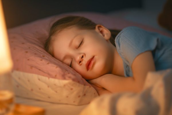 Young child sleeping peacefully in bed at night, representing common childhood sleep and bedwetting concerns