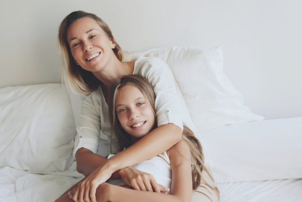 Mother with her child laying beed together in relation to bedwetting by age.